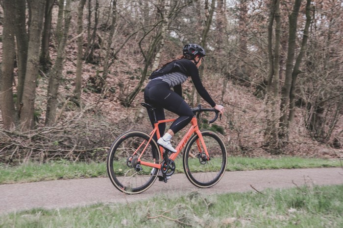 Woman riding an orange bike in the forest