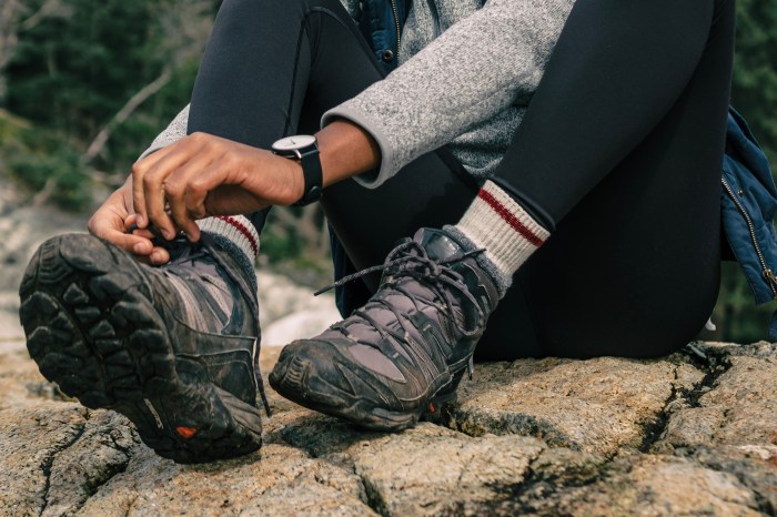 Woman tying hiking boots on a rock