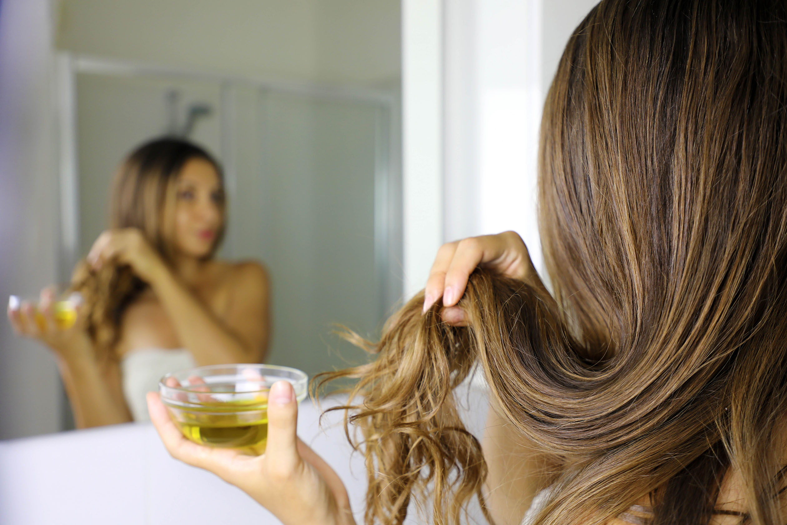 Woman using olive oil treatment on hair