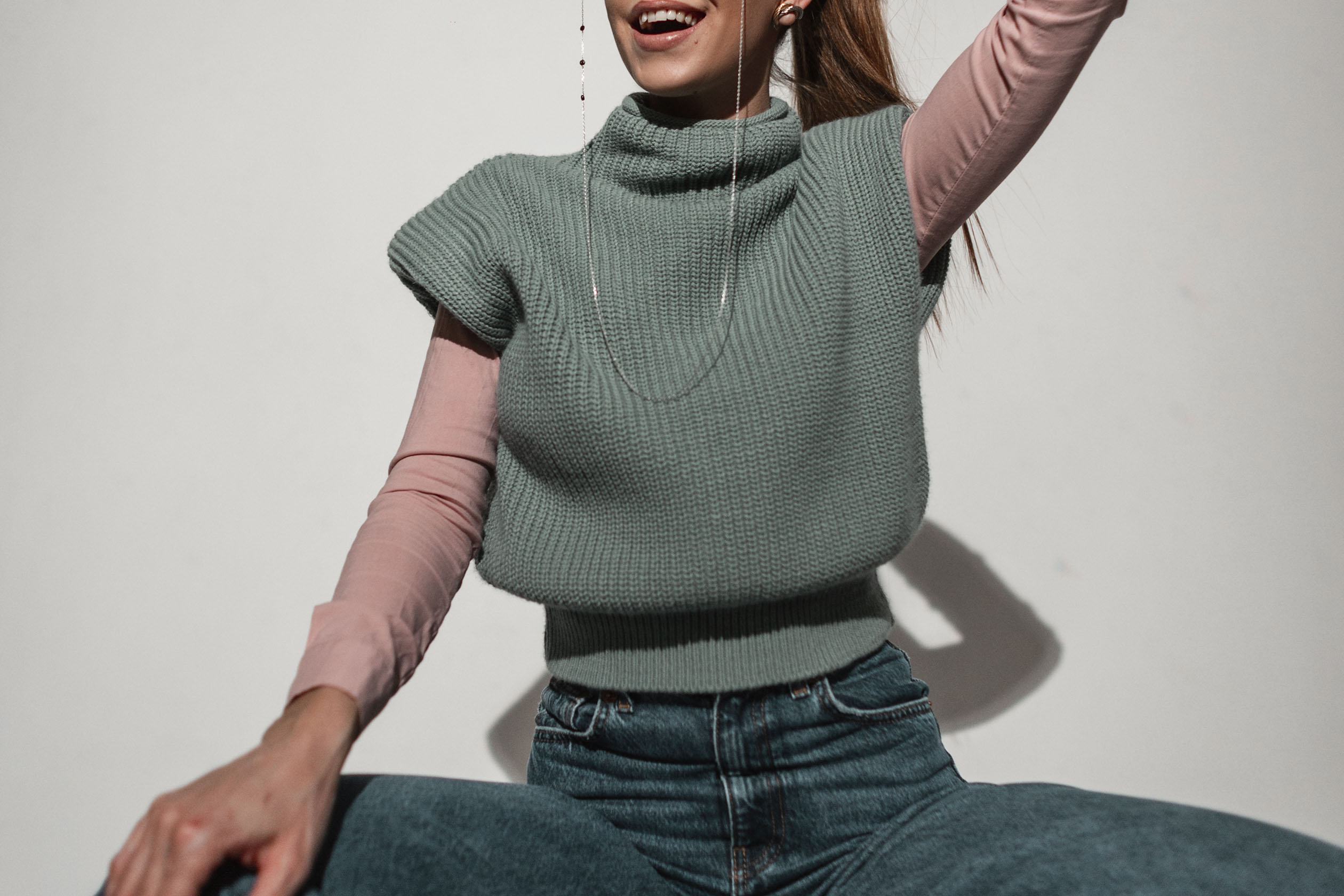 Woman wearing a sweater vest and jeans