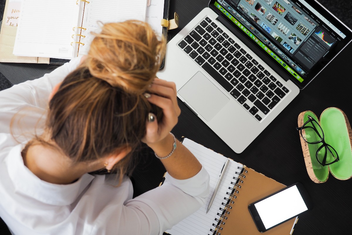 a woman with her head in her hands sitting at her desk