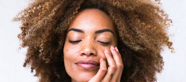 Woman with natural hair and her hand on her face