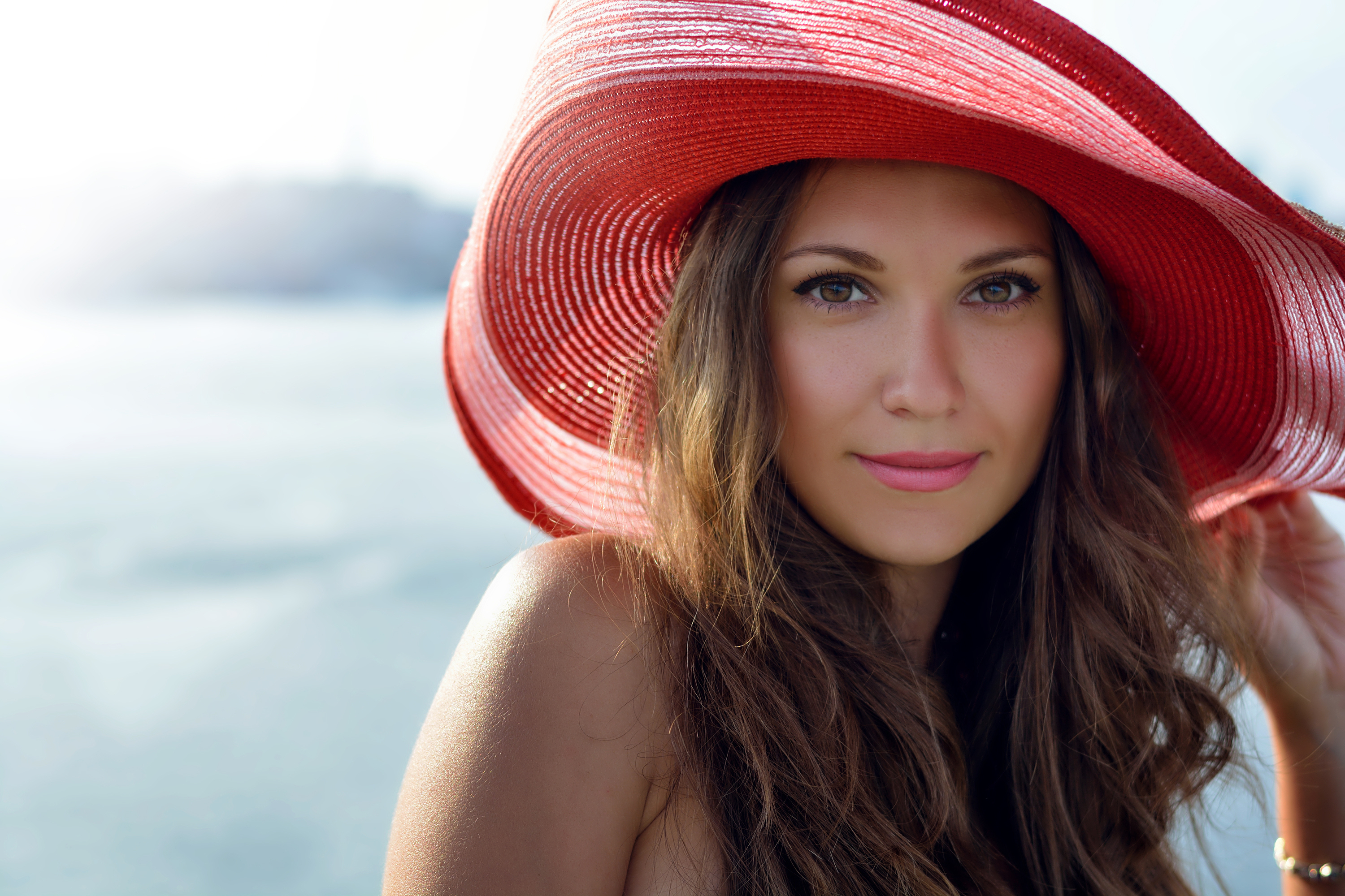 close up of woman wearing a red hat with beach in background