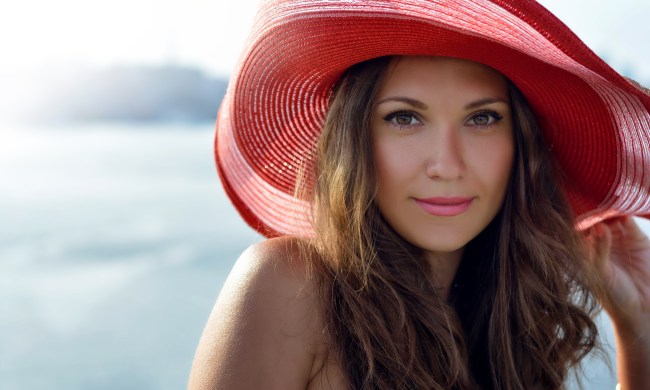 closeup of woman wearing a red hat with beach in background