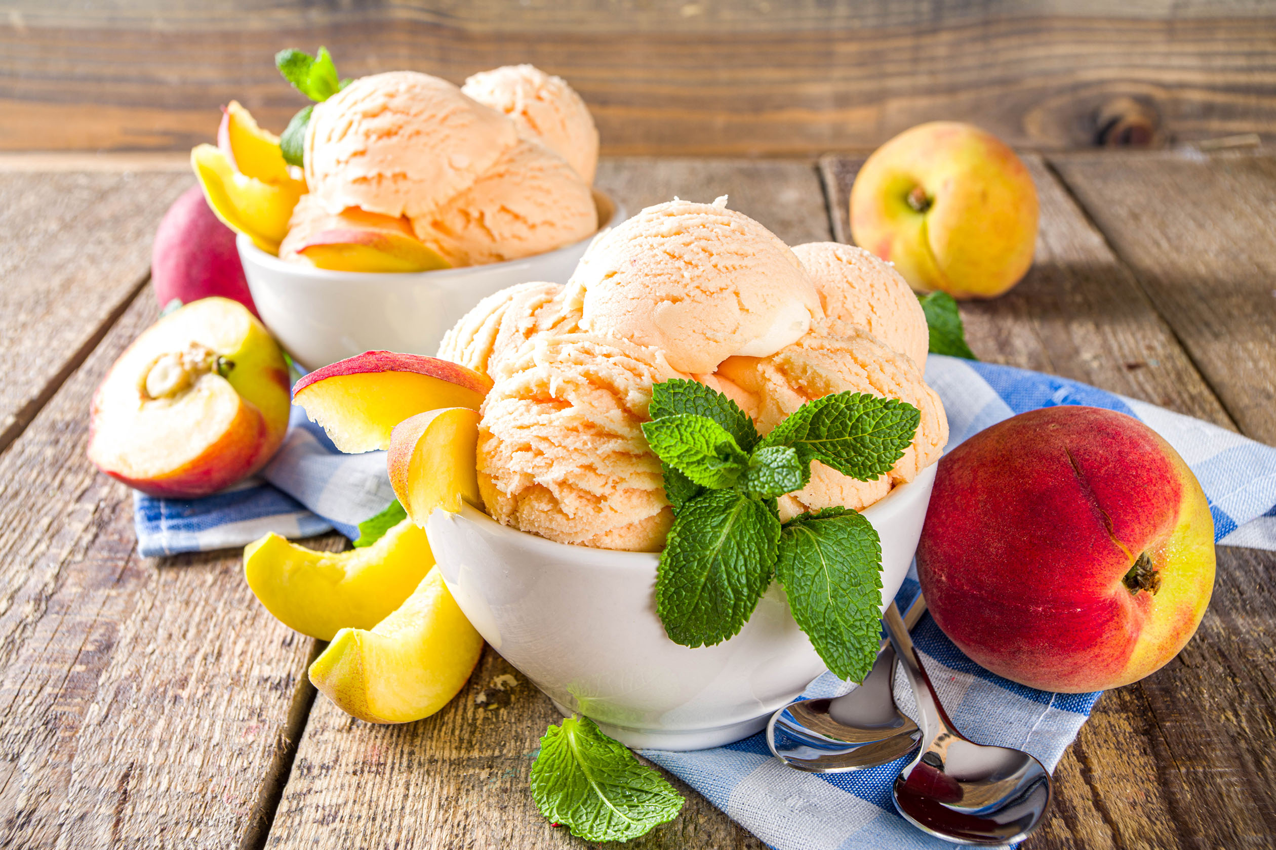 Peach ice cream in bowls with peaches