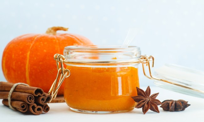Pumpkin spice body scrub in a jar, cinnamon sticks, and a pumpkin.