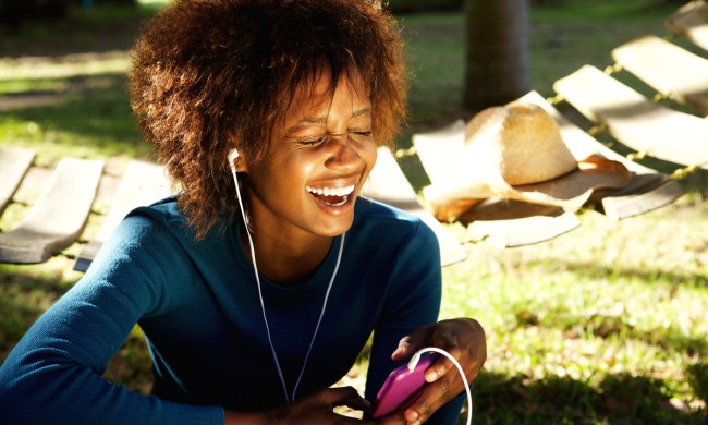 A woman laughing to something she's listening to.