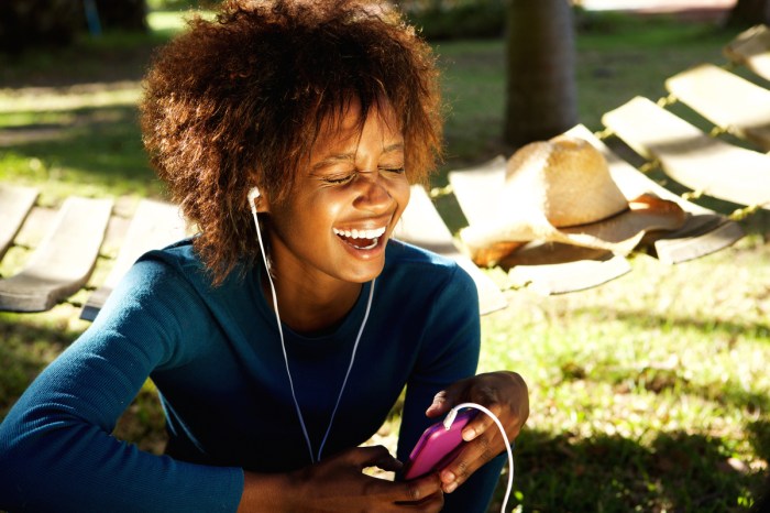 A woman laughing to something she's listening to.