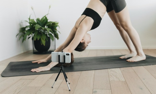 a woman in downward facing dog with her phone on a tripod