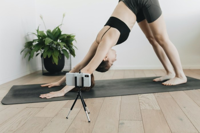 a woman in downward facing dog with her phone on a tripod