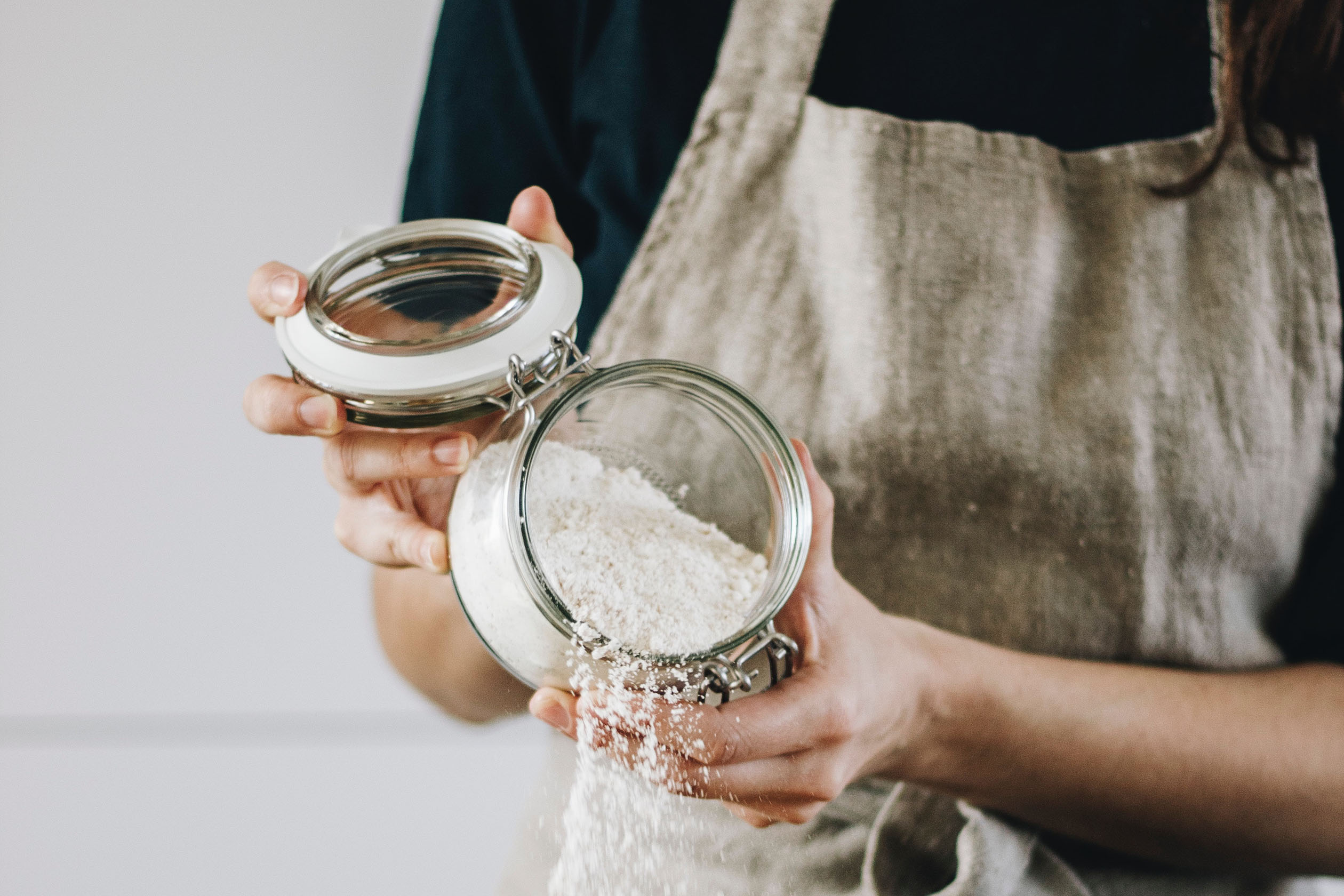 Baker pouring flour into a bowl