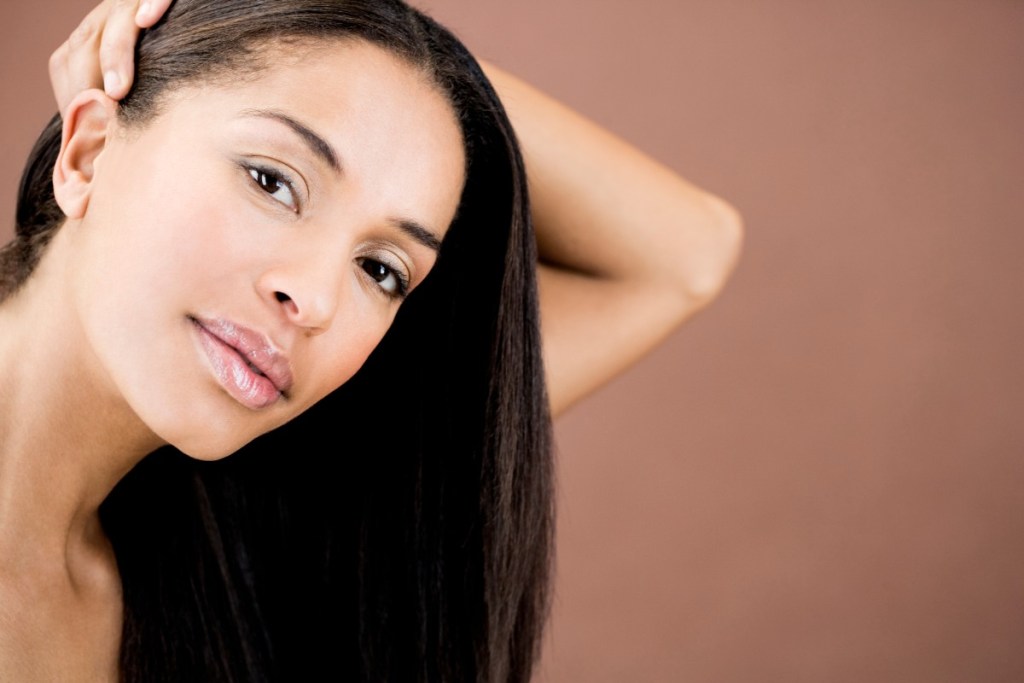 a beauty shot of a woman with straight hair against a brown background