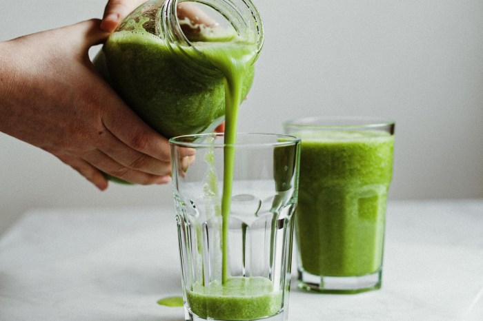Person pouring green smoothie into cups