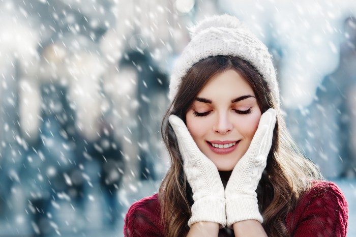 Closeup of woman in winter snowstorm with hands on face