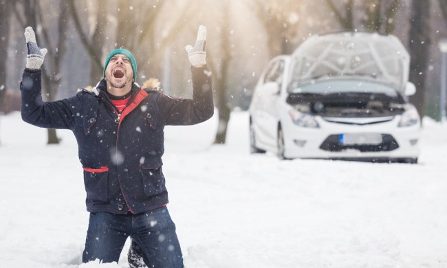 Man on knees in snowdrift screaming in front of a stalled car
