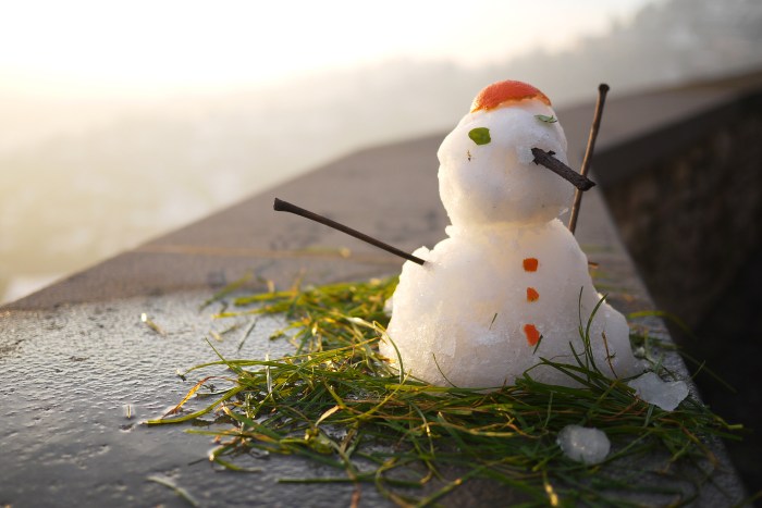 A melting snowman sitting on grass