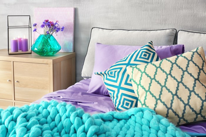 A well made bed with purple pillows and sheets and aqua accents