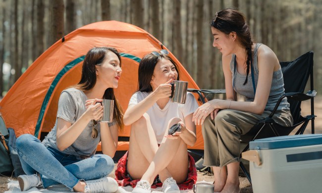 Three women camp outside of a tent