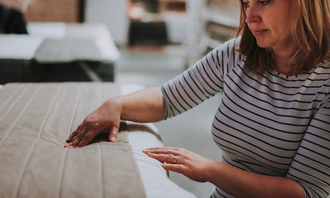 A woman wearing a striped shirt touches a mattress