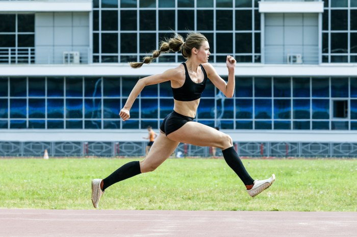 An action shot of a woman running while wearing compression stockings